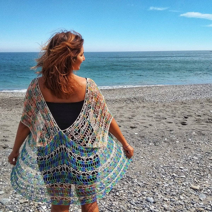Woman wearing Under The Sea crochet duster in front of a beach