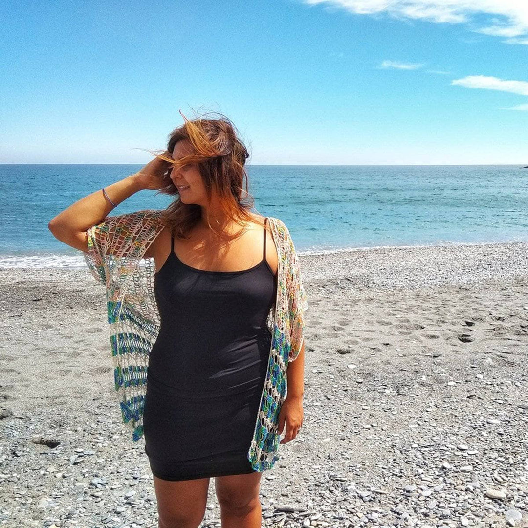 Woman wearing Under The Sea crochet duster in front of a beach