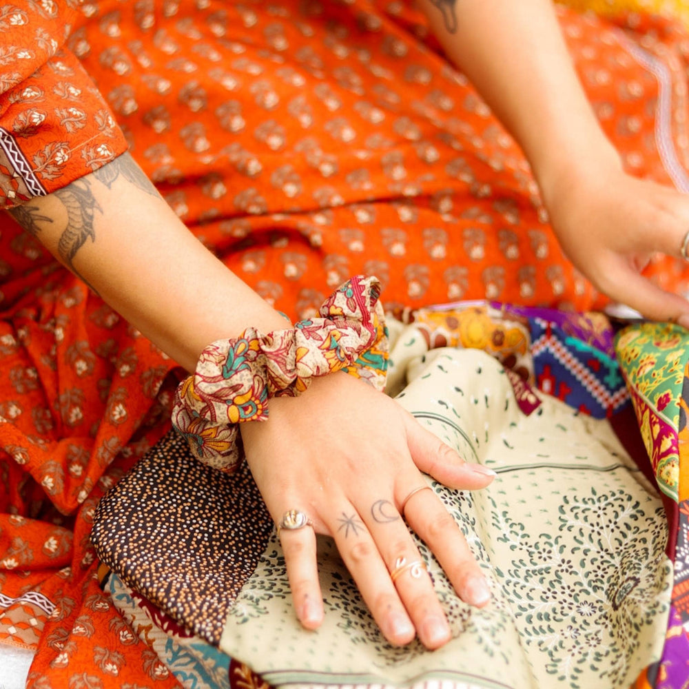 Model has her hand resting on a sari silk purse, around her wrist is a sari silk scrucnhie. 