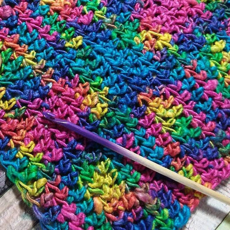 US 8/5mm Ombre Crochet Hook in purple over a multicolored crochet project