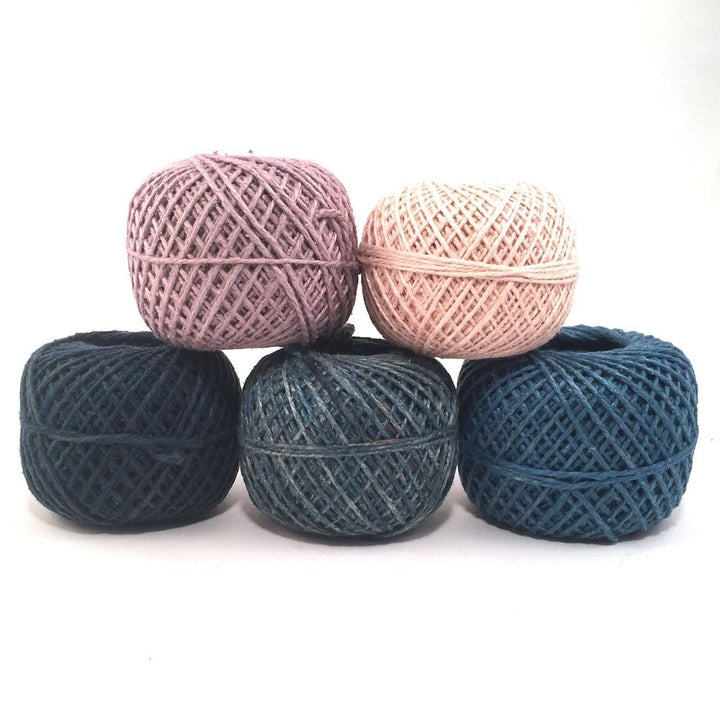 5 caked of 2 ply recycled silk herbal dyed yarn in front of a white background. 3 shades of blue, 1 pink, 1 purple.