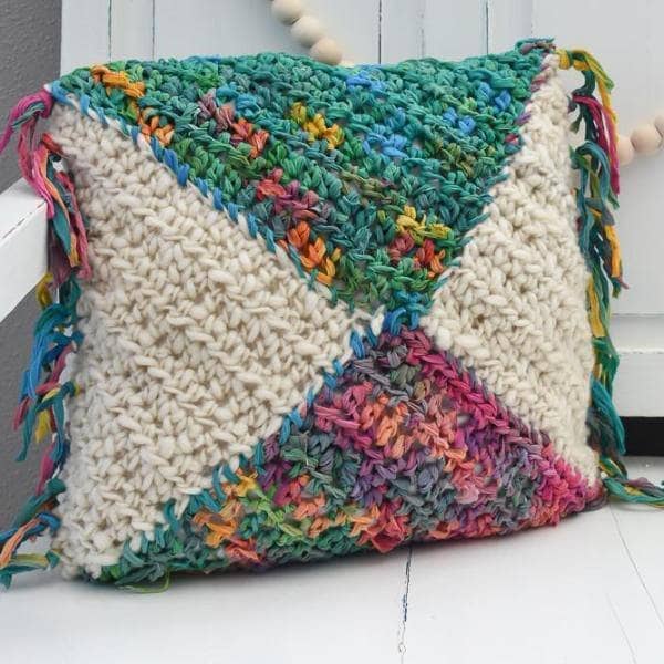 Watercolor crochet pillow sitting on a white surface 