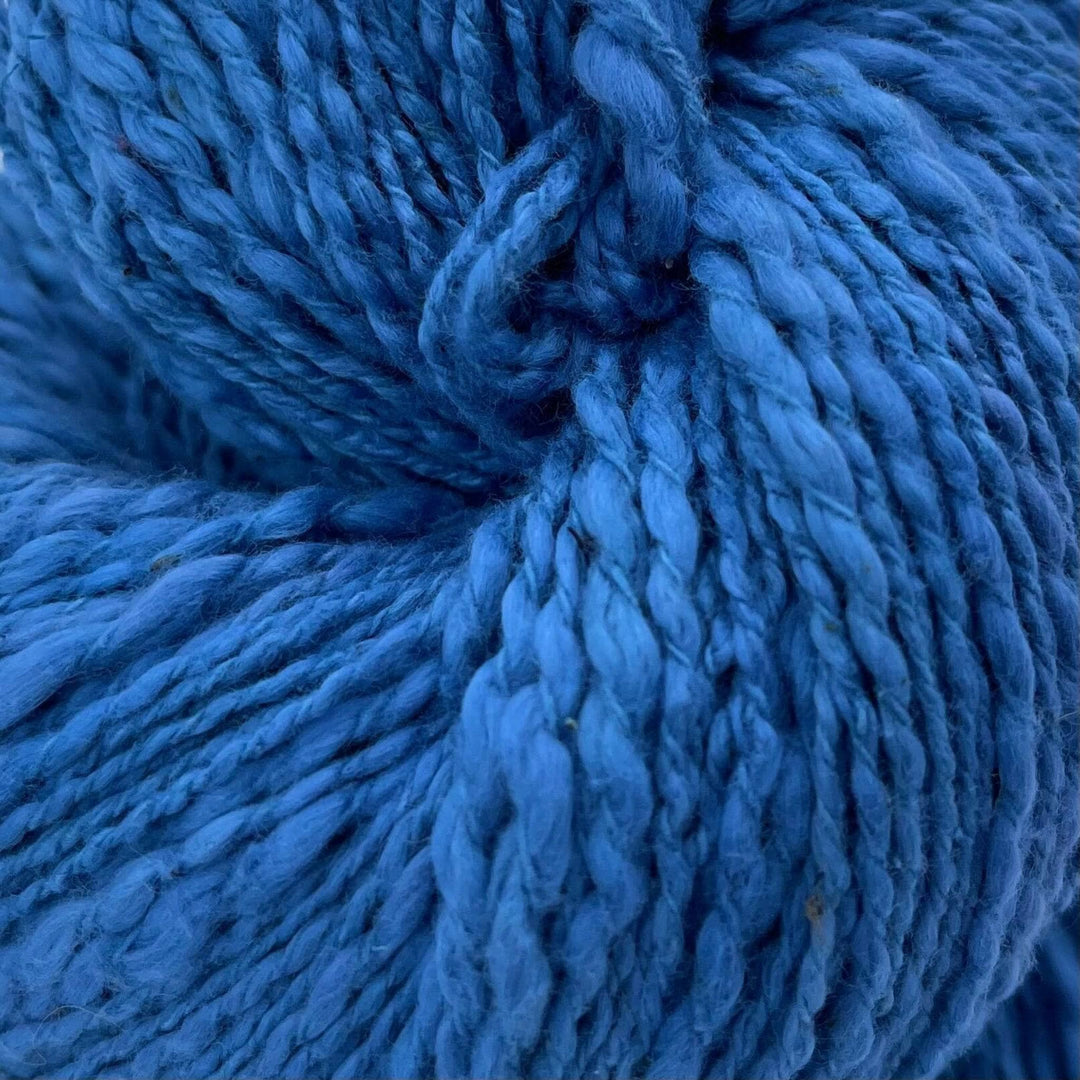 A close up of a skein of blue cotton yarn on a white background