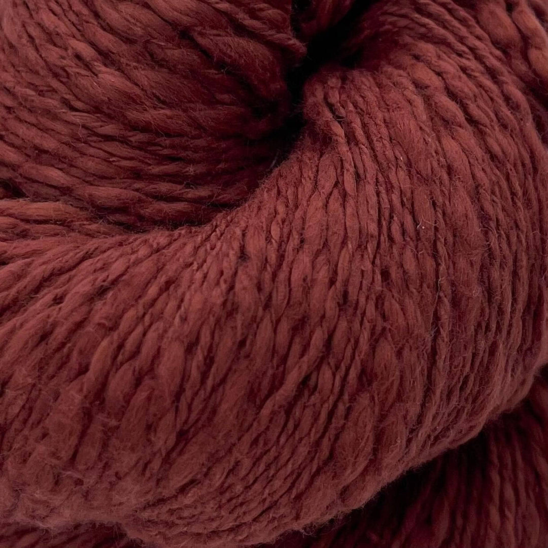 A close up of a skein of brown cotton yarn on a white background