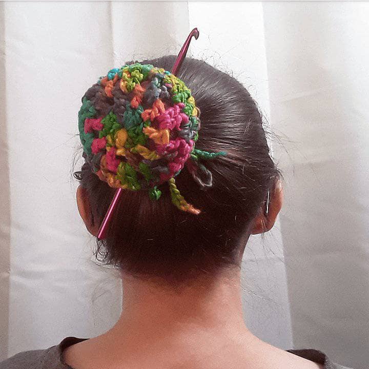 Woman wearing the Where's My Hook? crochet Bun Cover in Watercolors (multicolored) in front of a white wall
