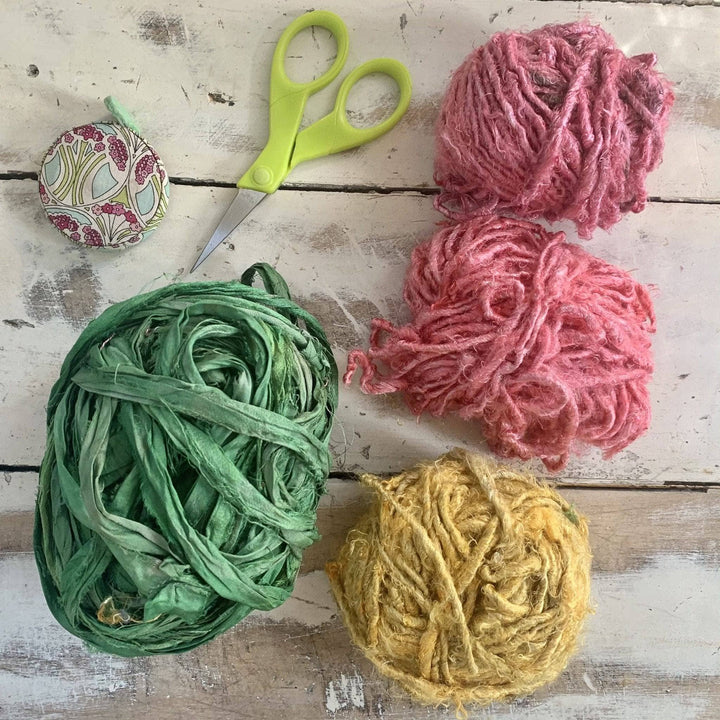 image of supplies needed to create a yarn flower crown. pickled pear sari silk ribbon yarn, coral, rich magenta, and sunflower banana fiber yarn (included). Scissors and tape measure (not included).