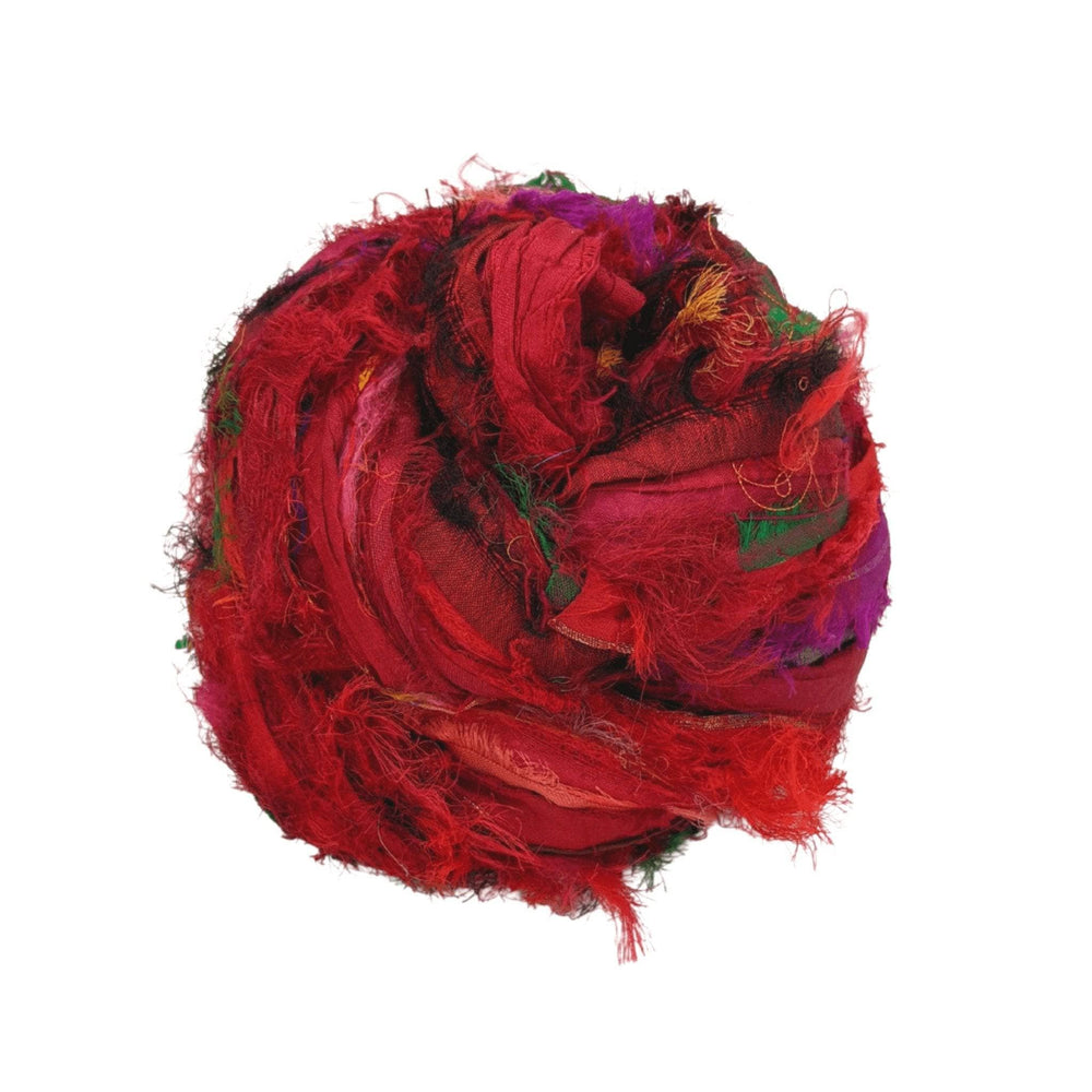 Skein of windswept sari silk ribbon yarn red in front of a white background. 