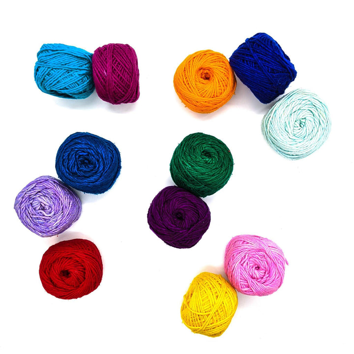 12 caked of silk roving worsted weight yarn scattered in front of a white background.