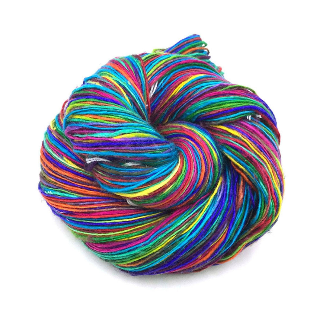 vibrant rainbow lace weight yarn in front of a white background.